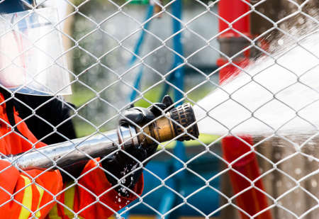 Fireman hosing water behind a fence