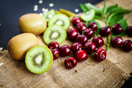 Organic kiwi & Cherry fruit isolated on the black backgroundの写真素材