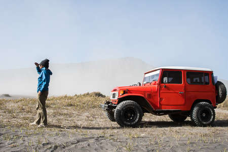 Man tourist on sand dune in desert during off road vehicle on sand, savannah at Bromo Mountain...