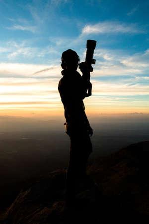 Silhouette of man hold up hands on the peak of mountain,success conceptの写真素材