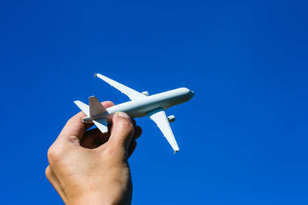 Airplane model in hand on sunny sky. Concepts of travel, transportation, transport, dreaming about...