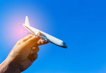 Airplane model in hand on sunny sky. Concepts of travel, transportation, transport, dreaming about holidaysの写真素材