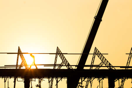 Silhouette engineer standing orders for construction crews to work on high ground heavy industry and safety concept over blurred natural background sunset pastelの写真素材