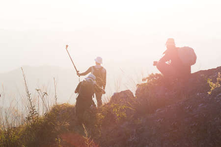 Silhouette of man hold up hands on the peak of mountain,success conceptの写真素材