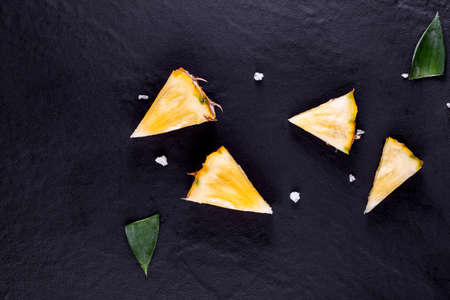 Fresh pineapple on black wood, black background.