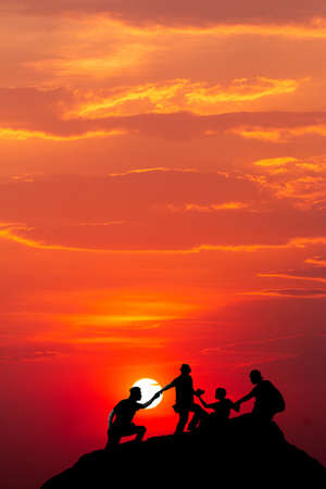 Silhouette of man hold up hands on the peak of mountain,success conceptの写真素材