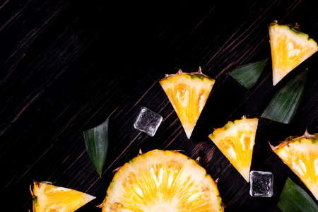 Fresh pineapple on black wood, black background