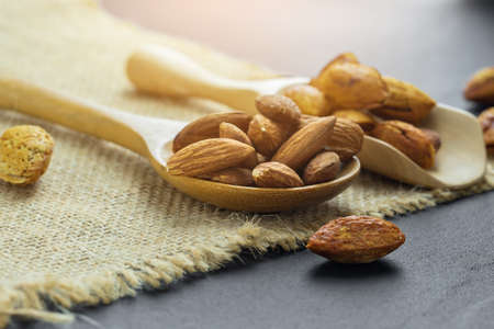 Almonds in a black bowl against dark rustic wooden background
