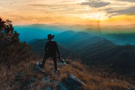 Silhouette of man hold up hands on the peak of mountain,success conceptの写真素材