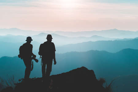 Silhouette of man hold up hands on the peak of mountain,success conceptの写真素材