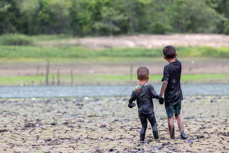 Funny portrait of smiling child with dirty face sitting and playing with fun on soilの写真素材