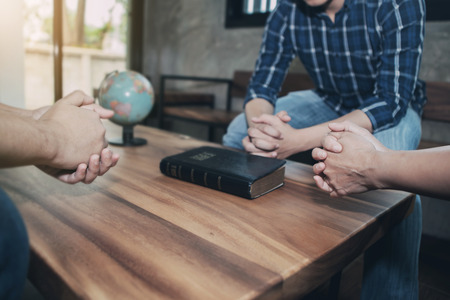 Three christian people pray together with bible and world globe on wooden tableの写真素材