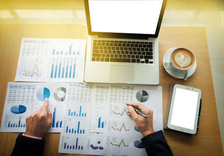 Business man working at office with laptop, tablet and graph data documents on his desk, top view.の写真素材