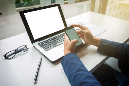 Young businessman working with laptop and smart phone on his desk in office.の写真素材