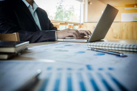 Young business manager working at office with laptop and financial data documents on his desk.の写真素材