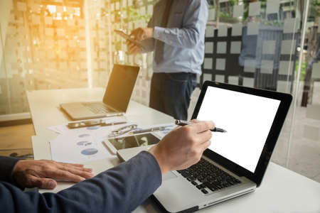 business documents on office table with smart phone and digital laptop and graph financial diagram and businessman working in the background, business concept.の写真素材