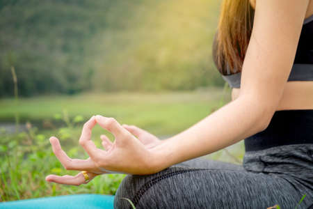 young woman sitting Yoga near river. Concept of healthy lifestyle and relaxation.