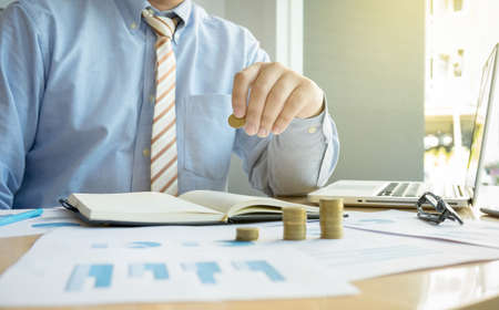 Close-up of Businessman putting coin to rising stack of coins.の写真素材