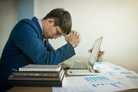 portrait of stressed business man with document graph in the office.の写真素材
