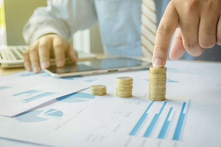 person pointing writing goals on a paper,writing business plan at workplace,man holding,papers,notes in documents,Saving money concept,graph, stacks of coins and chart.の写真素材