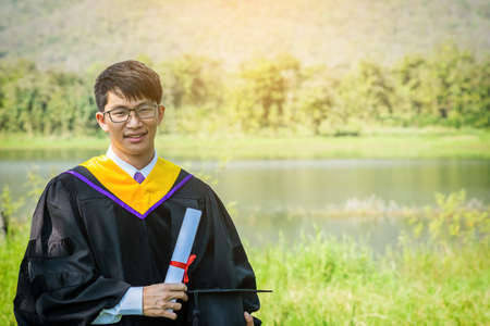 Graduation: Student smile holding certificate, graduation hat with Diploma With background in the nature.の写真素材