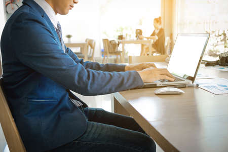Startup business people using laptop and summery business chart to analyze marketing situation. Working people doing  in coffee shop.の写真素材