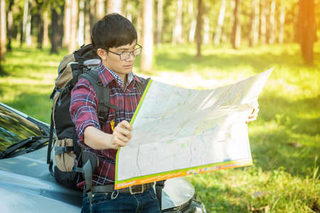 Young Man Traveler with backpack handle map relaxing outdoor on background Summer vacations and Lifestyle hiking concept.の写真素材