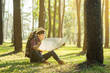Young Man Traveler with backpack, Viewing map relaxing outdoor on background Summer vacations and Lifestyle hiking concept.の写真素材