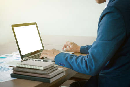 Image of business, Business man working at office with laptop and graph data documents on his desk.