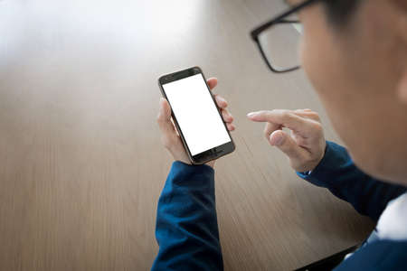 Close up of a businessman using mobile smart phone on wooden table, business concept.の写真素材