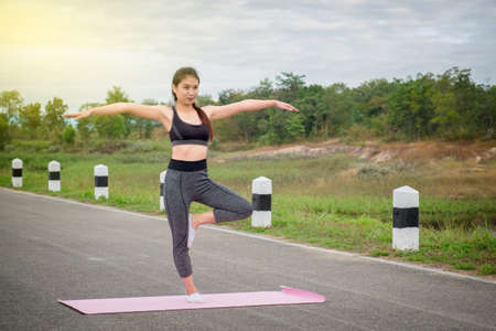 Woman practicing warrior yoga pose outdoors at nature background.の写真素材