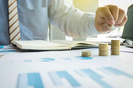 Close-up of Businessman putting coin to rising stack of coins.の写真素材