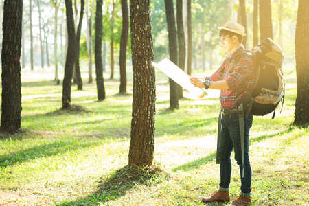Young Man Traveler with backpack, Viewing map relaxing outdoor on background Summer vacations and...