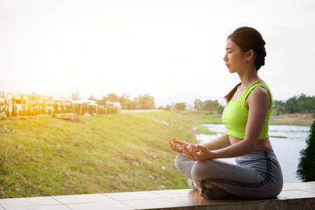 Young fitness woman practicing yoga on the field, healthy lifestyle concept.の写真素材