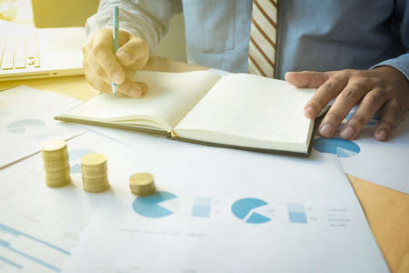 Closeup shot of hands counting coins and making notes on paper.の写真素材