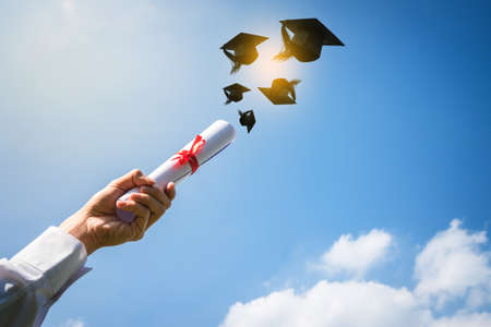 Graduates hands throwing graduation hats.の写真素材