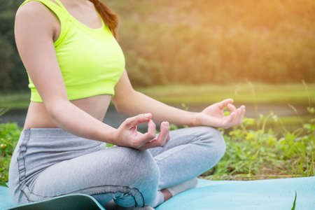 Young fitness woman practicing yoga on the field, healthy lifestyle concept.