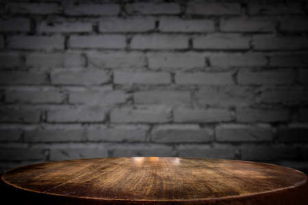 Selected focus empty brown wooden table and wall texture or old black brick wall blur background...