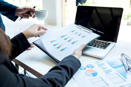 Business people discussing the charts and graphs showing the results of their successful teamwork,...