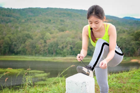 Young woman tying her sports shoes on exercising mat. Concept of healthy lifestyle and relaxation.の写真素材