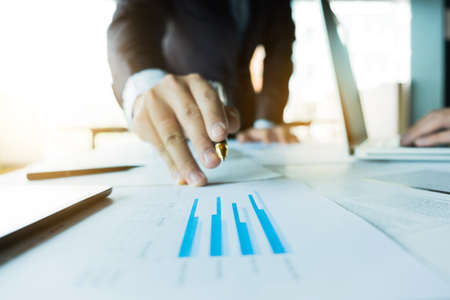 Businessman analysis on graph data paper with business colleagues using laptop at the office.の写真素材