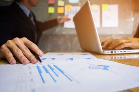 Business executive pointing graph presentation to colleagues in office, during meeting, explaining,...
