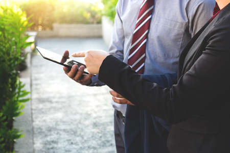 Business team two colleagues being discussing the new project financial plan on digital tablet outdoor.の写真素材