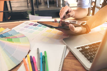 Color samples, color swatch samples, Draw architecture, Graphic designer selecting on colour chart, pens at workplace, Working with laptop and tablet on wooden desk.の写真素材