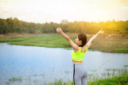 Sport girl standing with raised arms and enjoying a beautiful nature, healthy lifestyle concept.の写真素材