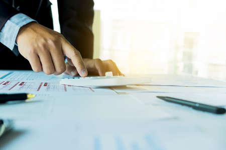 Businessman analysis on calculator, new plan financial graph data at the office, business concept.の写真素材