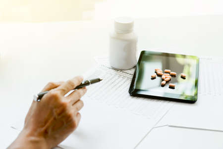 View of hand's doctor pointing to pad, drug and equipment on foreground table, Health care and Medical concept.の写真素材