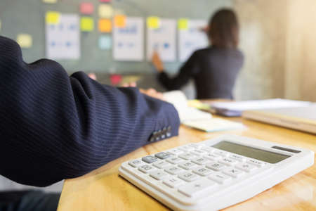 Close-up of calculator, business man and secretary presentation report, two colleague excultive conference presentating chart report of new plan marketing to development consultating business in company.の写真素材
