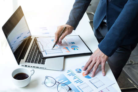 Business man working at office with laptop and documents on his desk. Analyze plans, papers, hands keyboard .の写真素材