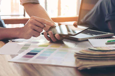 Color samples, color swatch samples, Draw architecture, Graphic designer selecting on colour chart, pens at workplace, Working with laptop and tablet on wooden desk.の写真素材